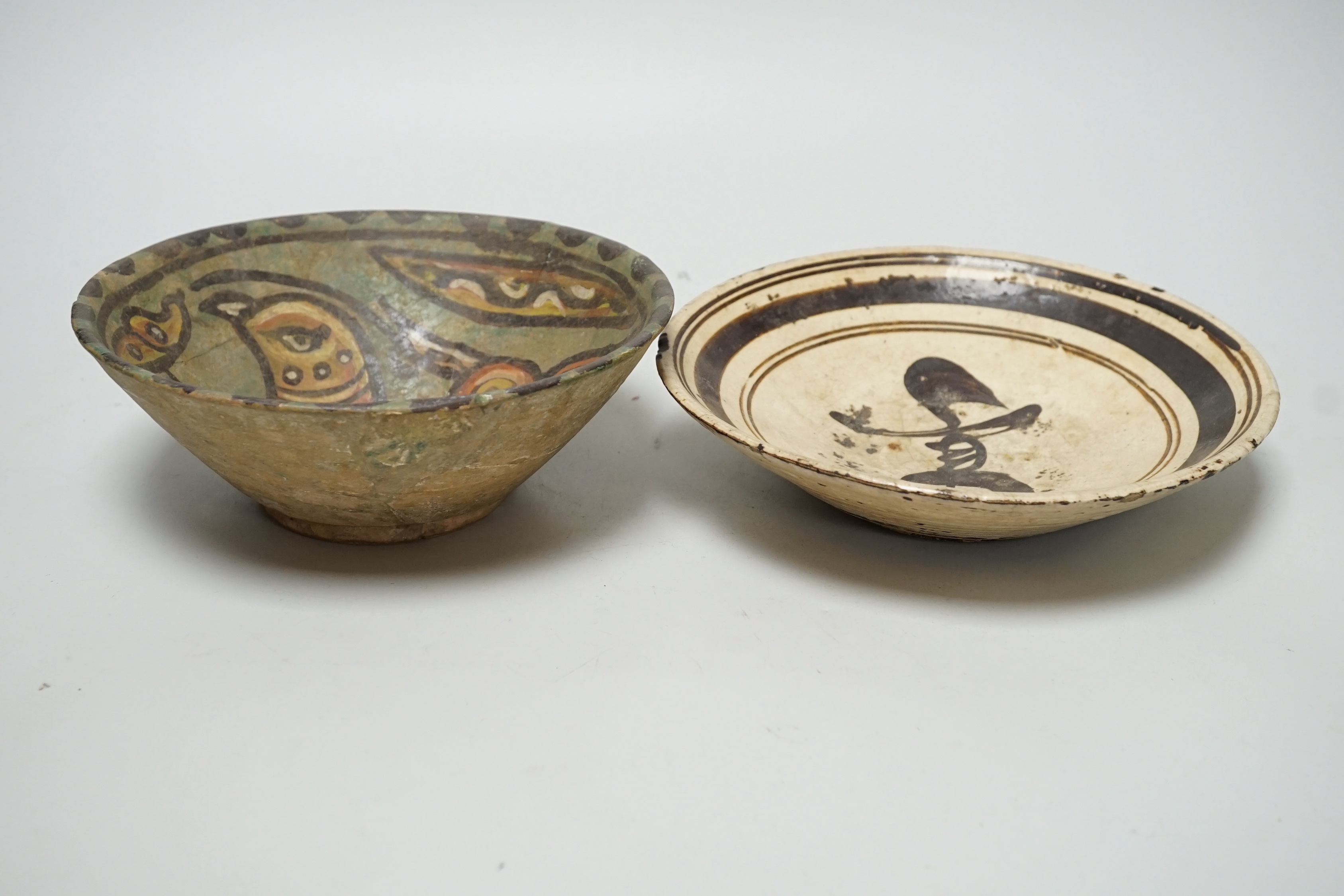 A 12th century Nishapur pottery bowl, painted with a bird, cracked and restored, together with a Chinese Cizhou pottery character dish, Yuan dynasty, largest 19cm diameter (2)